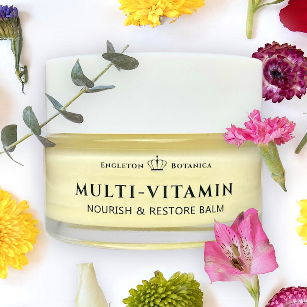Multi-Vitamin Nourish & Restore Balm by Engleton Botanica surrounded by flowers on a white background