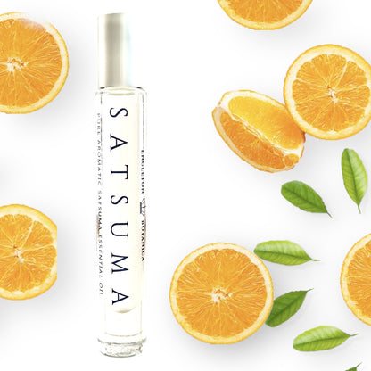 Satsuma essential oil perfume bottle with sliced oranges and leaves on a white background