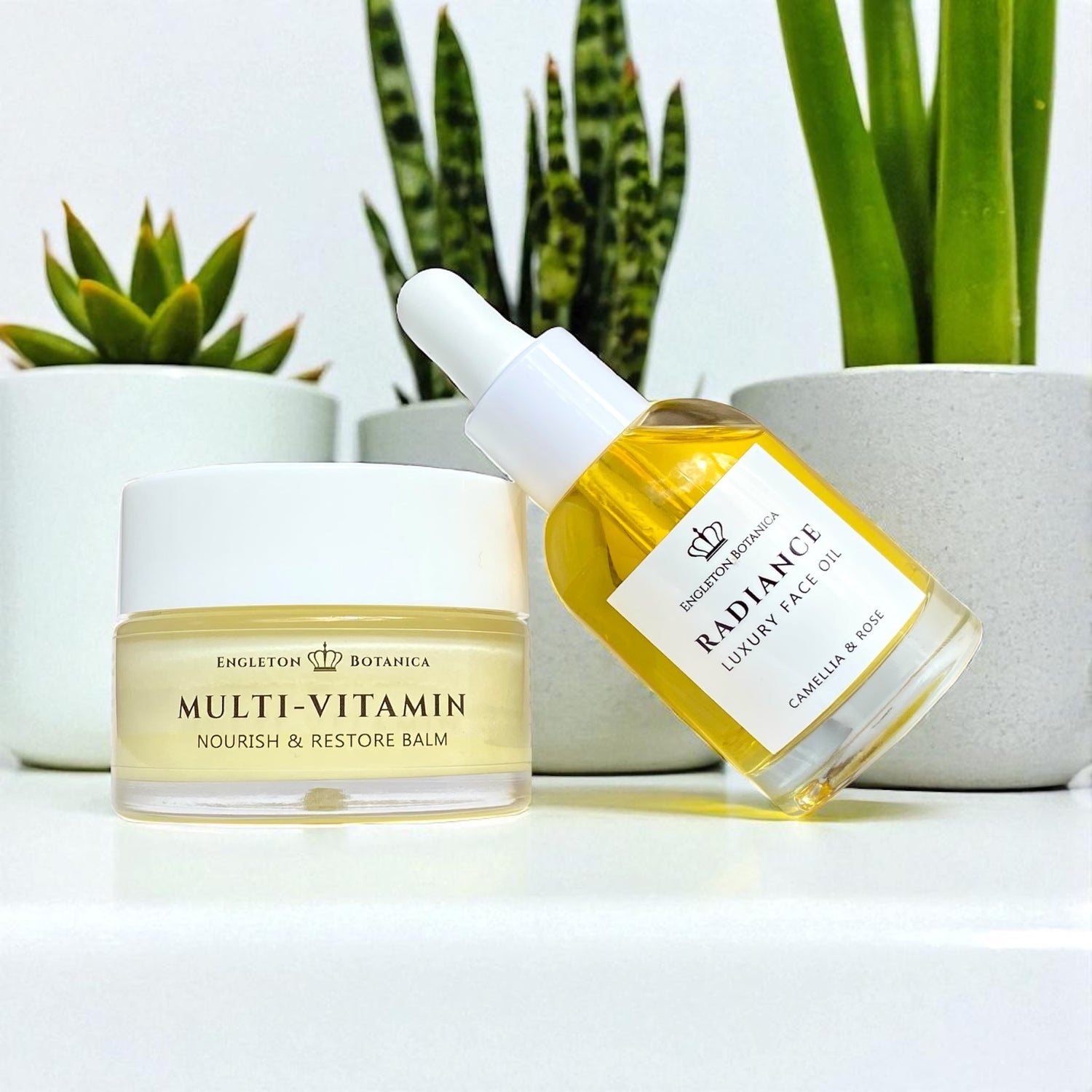 Cosmetic products including a balm and a dropper bottle with plants in the background