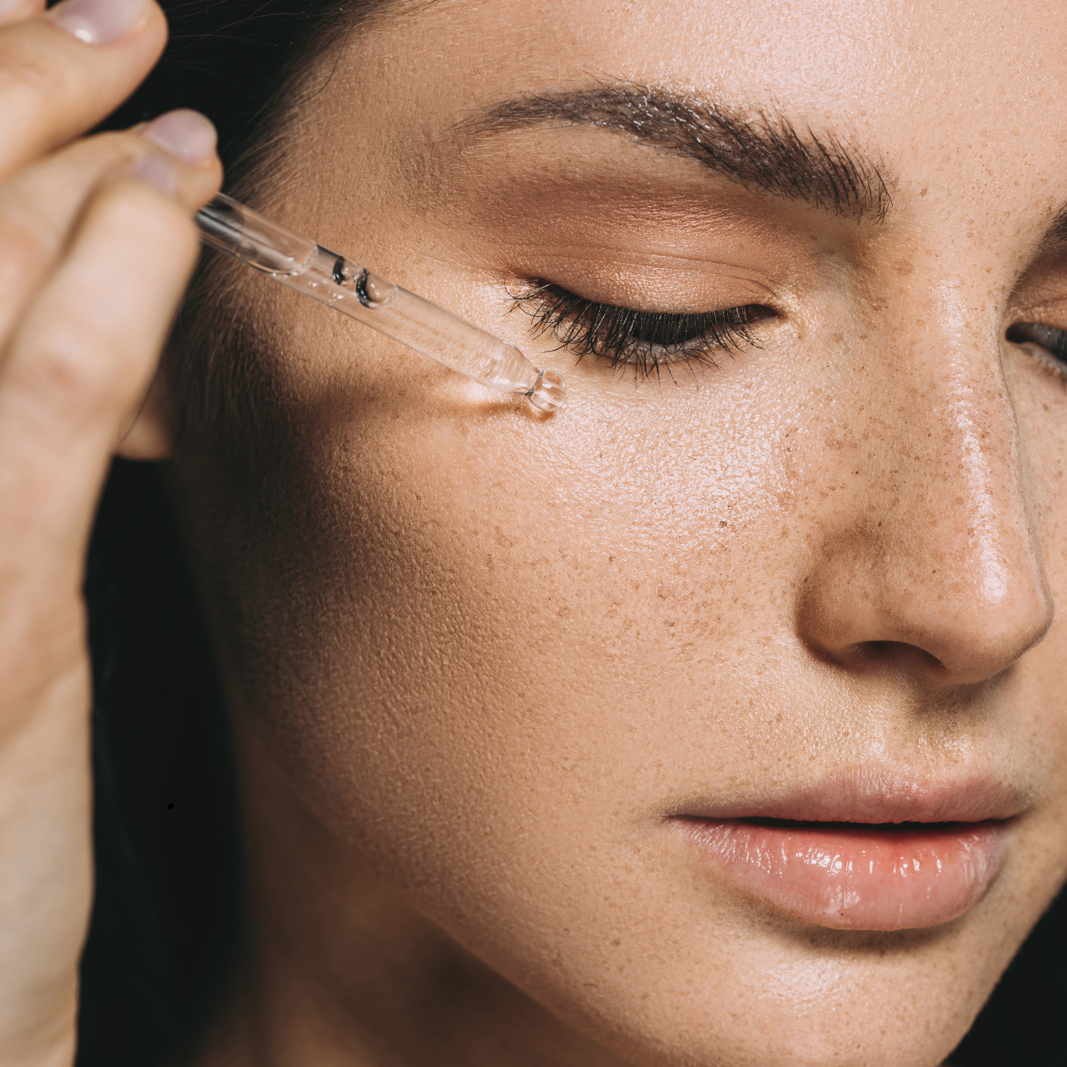 Close-up of a woman applying a dropper to her eye with a blurred background