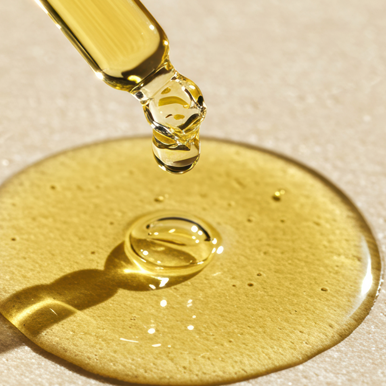 Gold dropper with a drop of vitamin E on a beige background